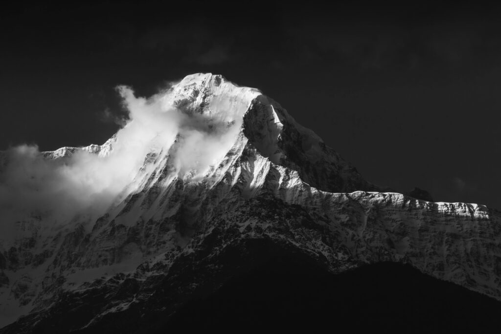 Stunning black and white view of Annapurna mountains with snowcapped peaks and dramatic clouds.